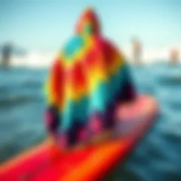 A vibrant changing poncho displayed on a surfboard with ocean waves in the background